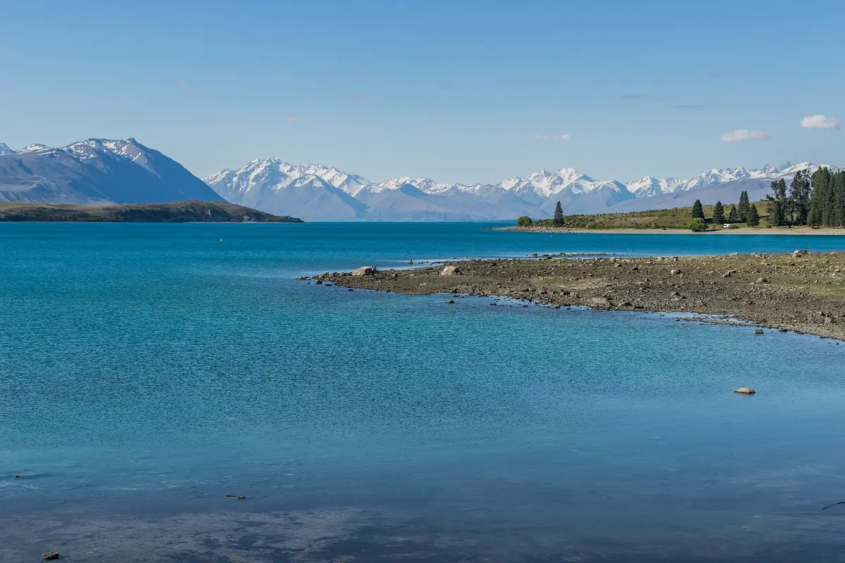 The shore of Lake Tekapo with mountains behind