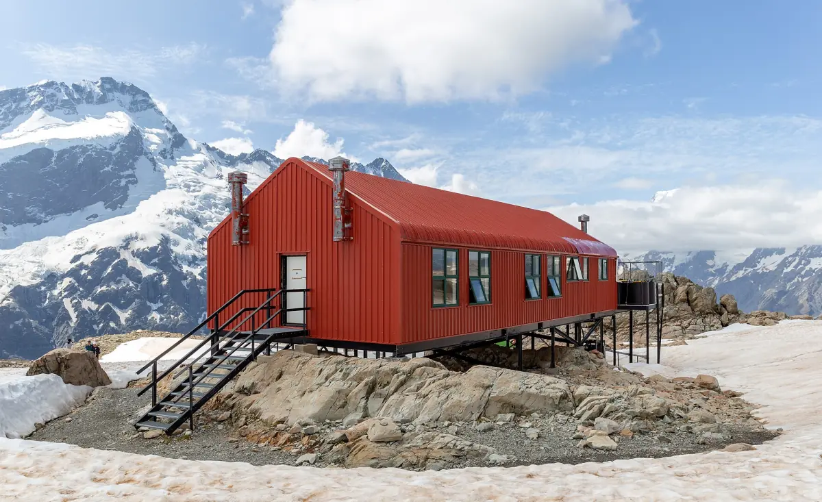 The red Mueller Hut on a snowy ridge